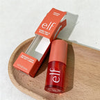 Red lip tint with mirror and packaging on a wooden surface