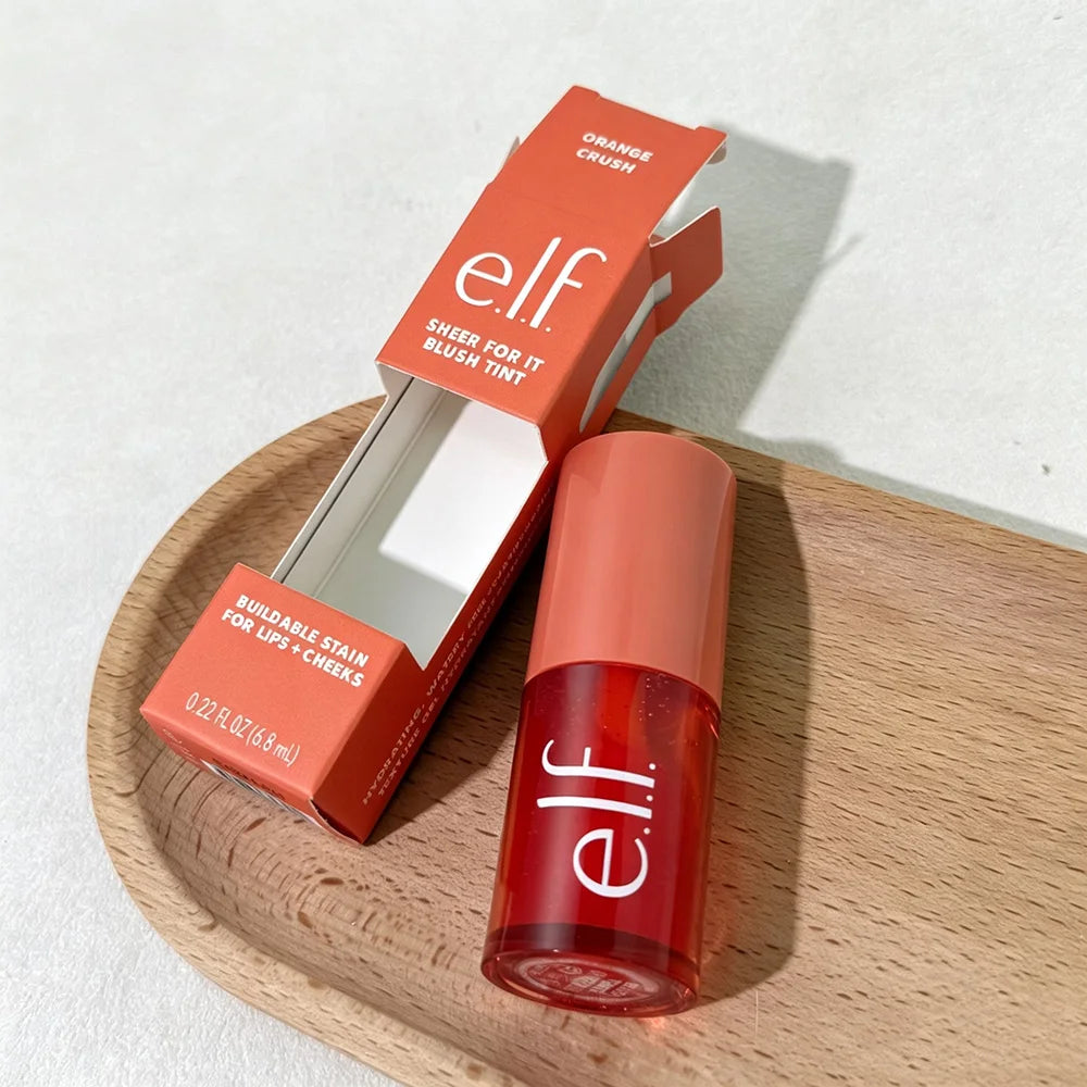 Red lip tint with mirror and packaging on a wooden surface
